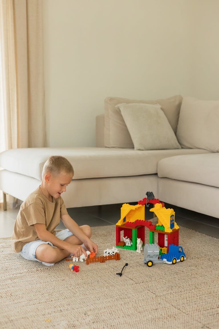 A young boy plays with colorful toy building blocks in a cozy living room setting, promoting creativity.