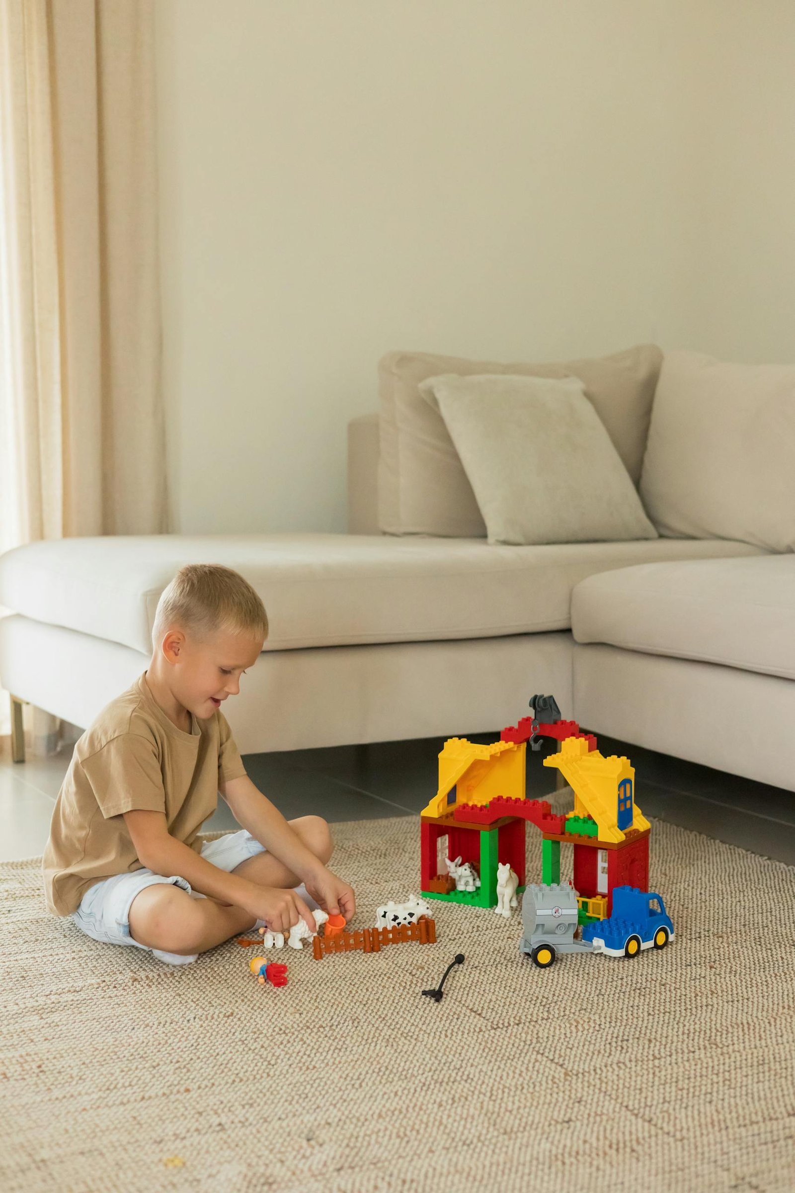 A young boy plays with colorful toy building blocks in a cozy living room setting, promoting creativity.
